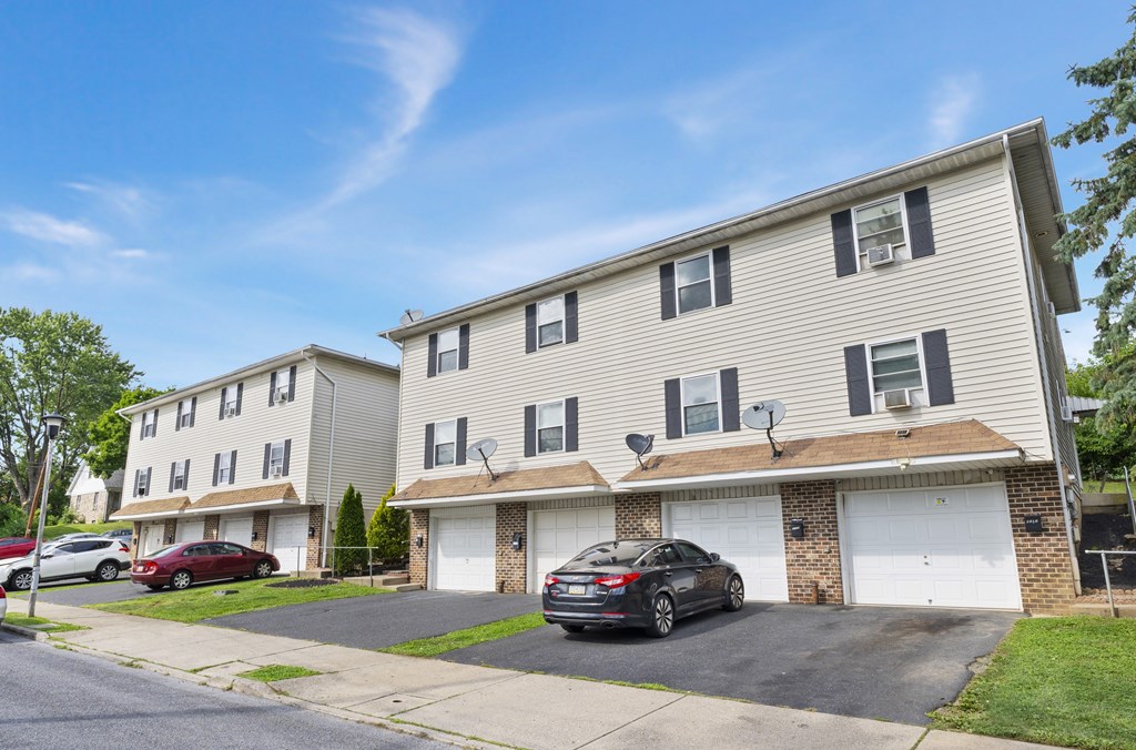 A two-story apartment building with a car parked in front.