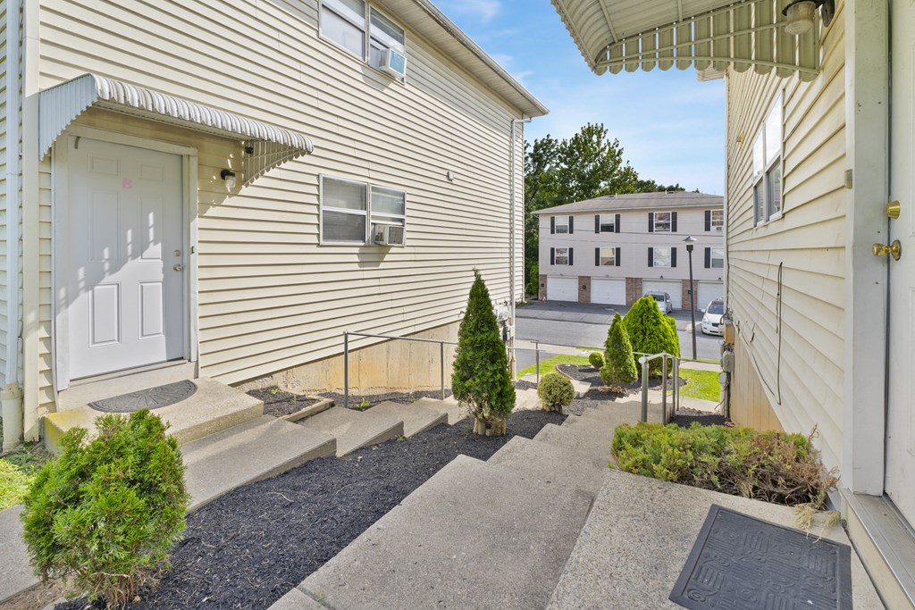 A small tree is in the front yard of a tan house.
