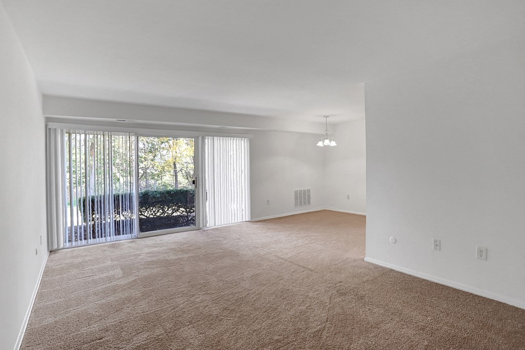 an empty living room with a sliding glass door to a patio
