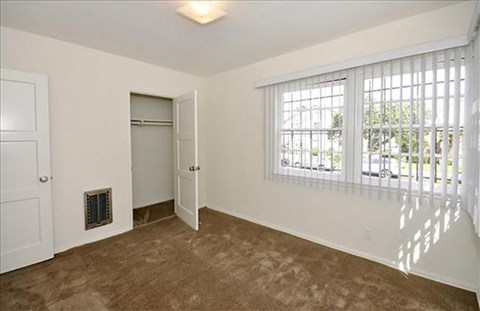 an empty living room with a window and a door to a closet