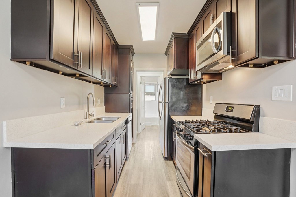 A modern kitchen with dark brown cabinets and stainless steel appliances.