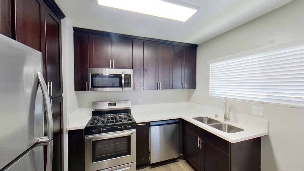 a kitchen with dark wood cabinets and stainless steel appliances