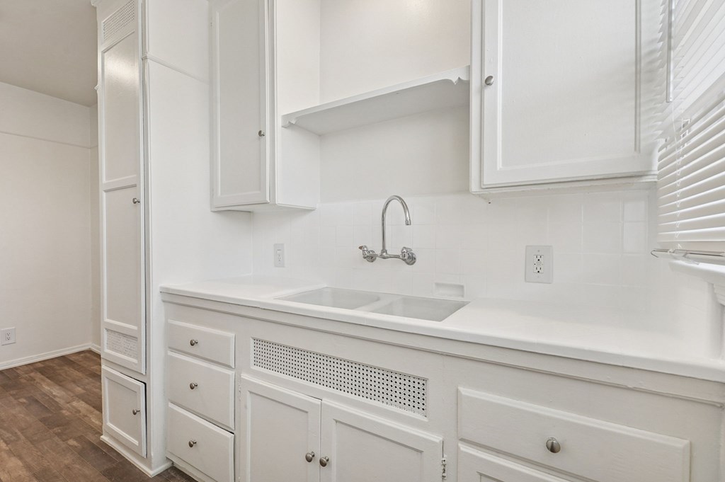 A white kitchen with a sink and cabinets.