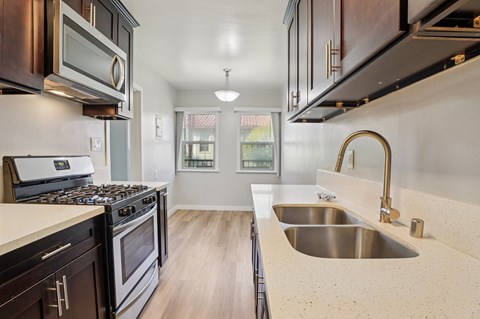 A kitchen with dark wood cabinets and a stainless steel sink.