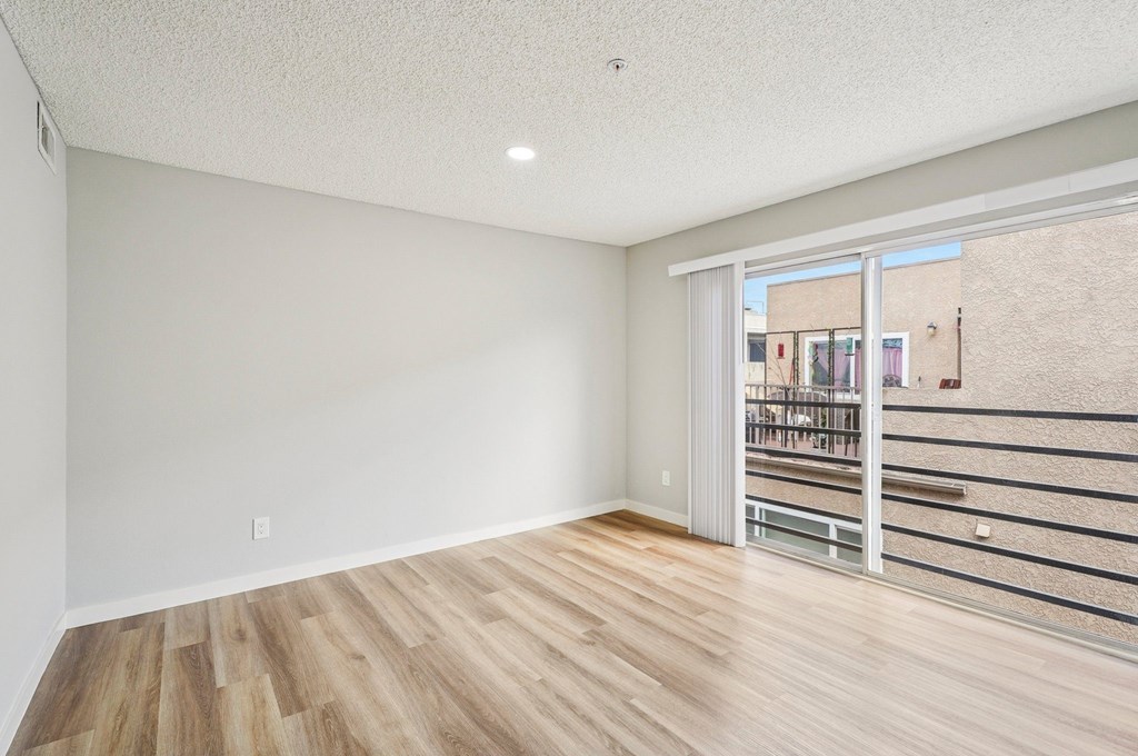 A room with wooden flooring and a sliding glass door.