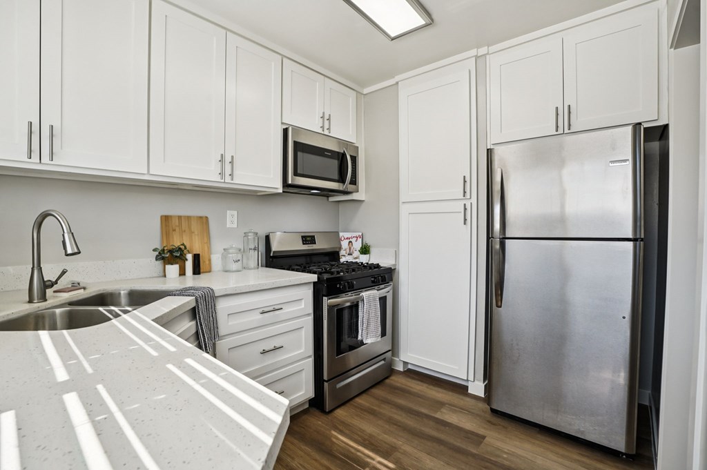 A kitchen with white cabinets and a stainless steel refrigerator.