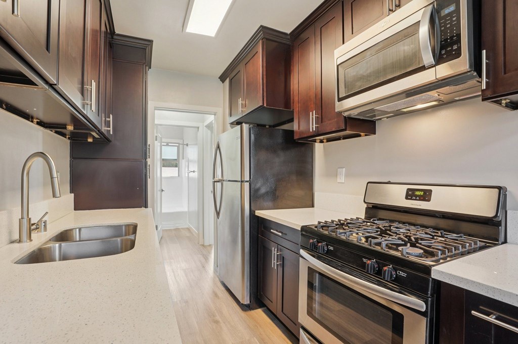 A modern kitchen with dark wood cabinets and stainless steel appliances.