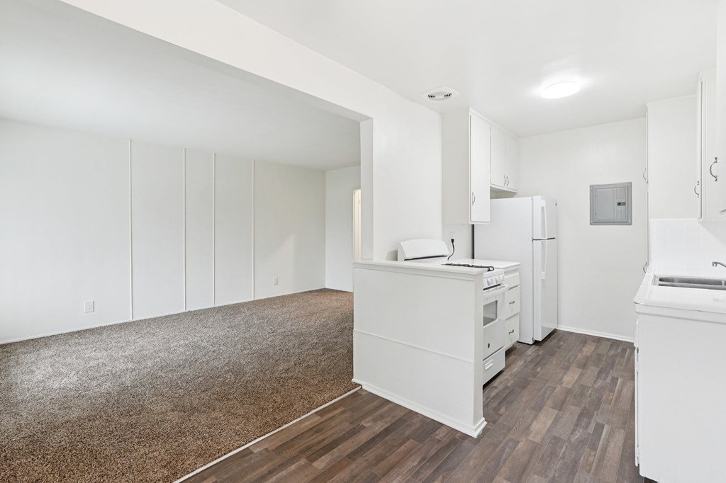 A kitchen with white cabinets and a white fridge.