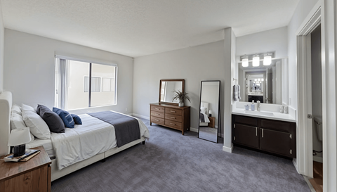 A bedroom with a large bed, dresser, and mirror.