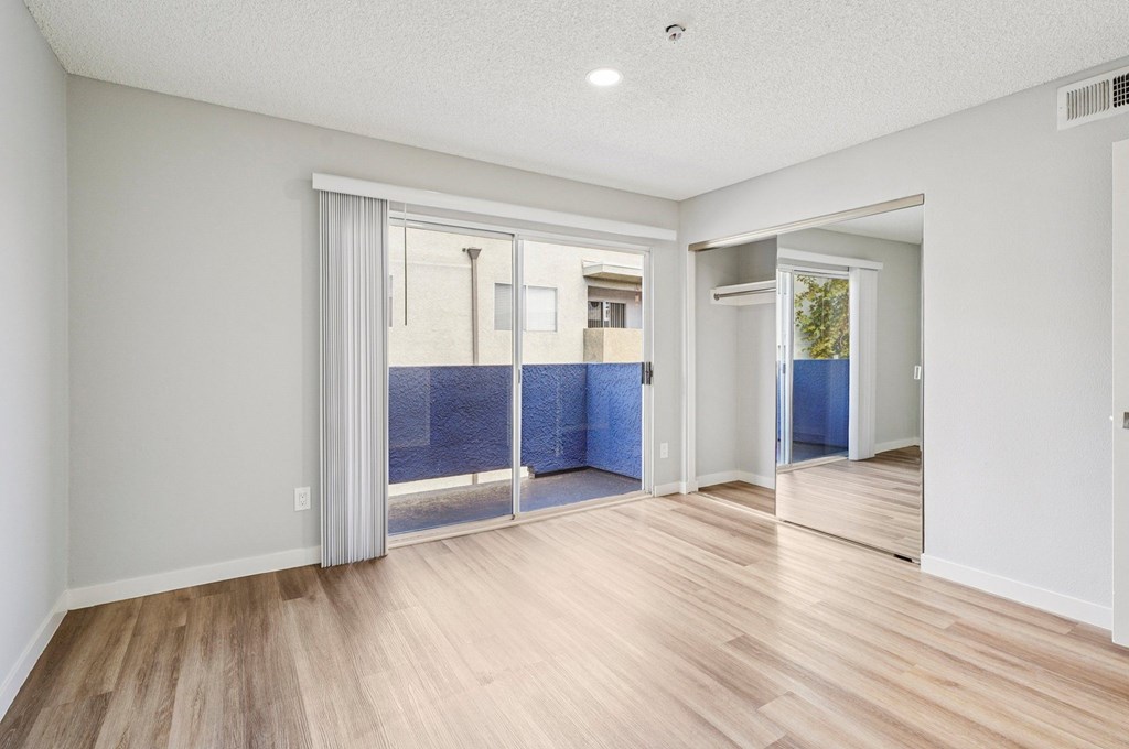 A room with a sliding glass door leading to a balcony.