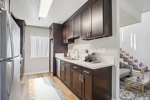 A modern kitchen with dark brown cabinets and a white countertop.