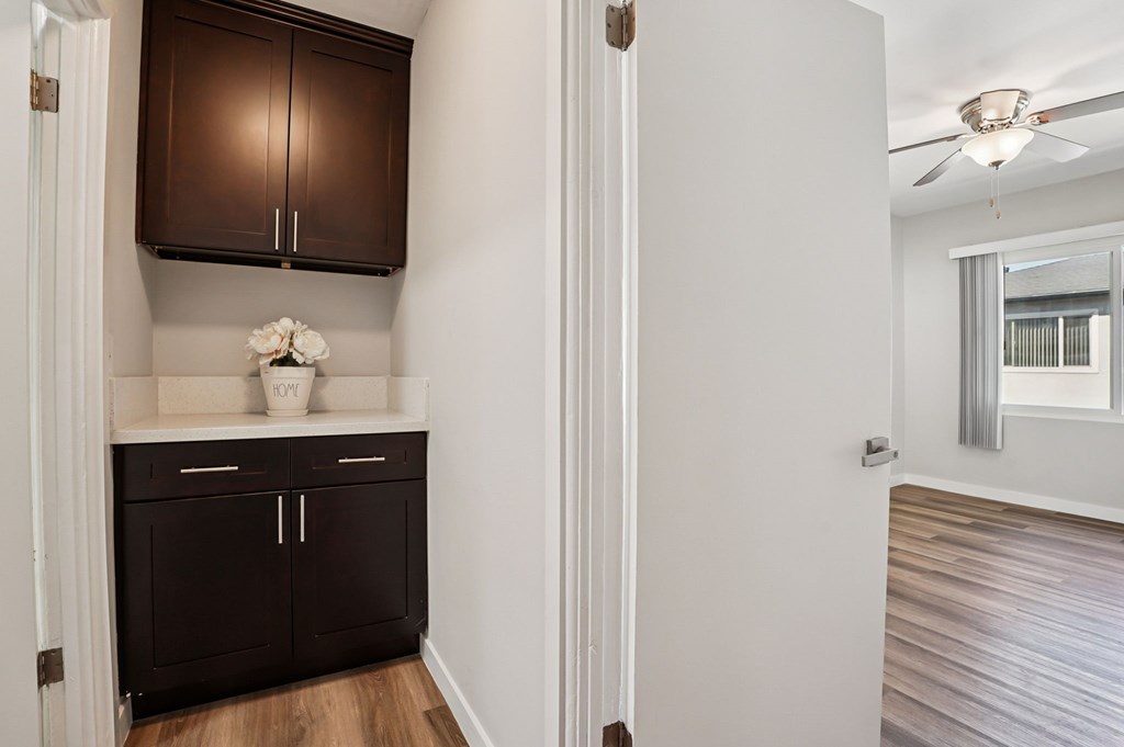 A kitchen with dark brown cabinets and a white flower on the counter.
