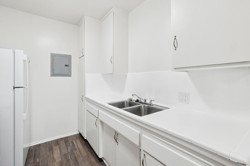 A kitchen with white cabinets and a white fridge.