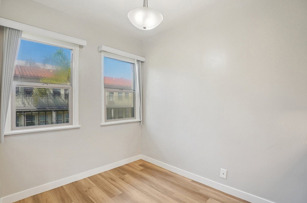 A room with two windows and a wooden floor.