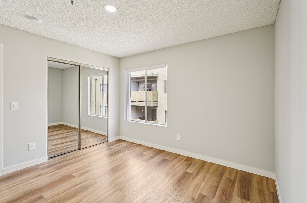 A room with a sliding glass door and wooden flooring.