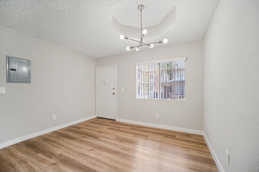A room with a wooden floor and a window with blinds.