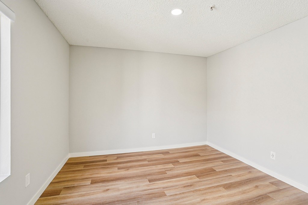 A room with wooden flooring and white walls.