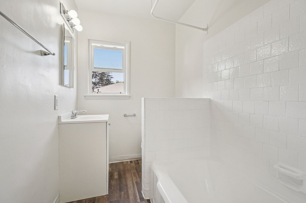 A white bathroom with a window and a tub.
