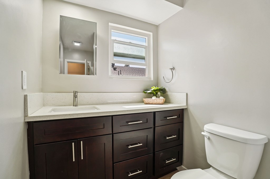 A bathroom with a white toilet and a mirror above a sink.
