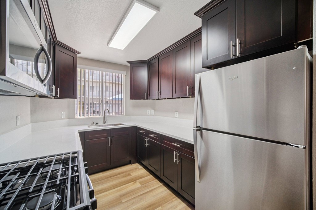 A modern kitchen with dark wood cabinets and stainless steel appliances.