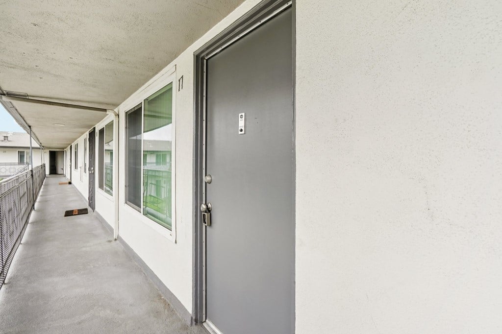 A grey door is on the right side of a white wall.