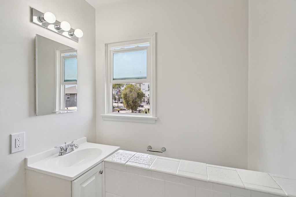 A bathroom with a white sink and a window.