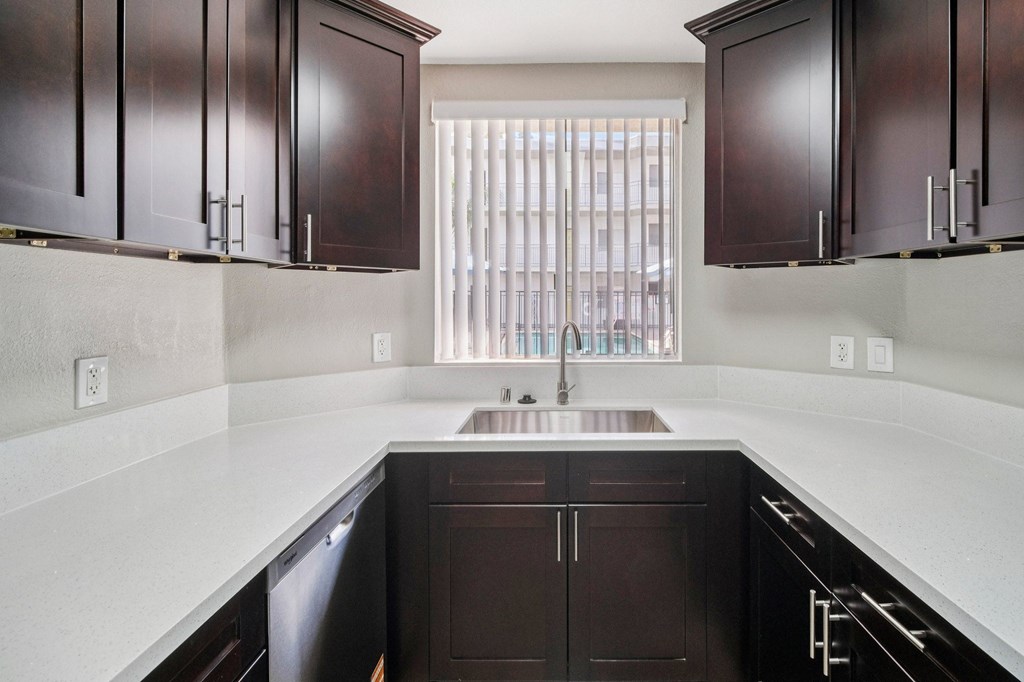 A kitchen with dark brown cabinets and a stainless steel dishwasher.