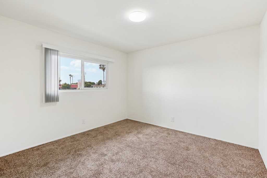 Empty room with carpeted floor and a window.