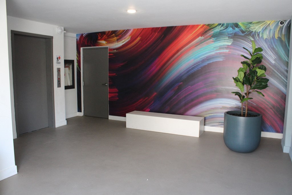 a large room with a plant and a painting on the wall