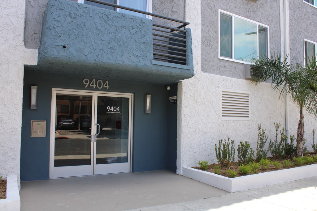 the entrance to a building with a glass door and a balcony