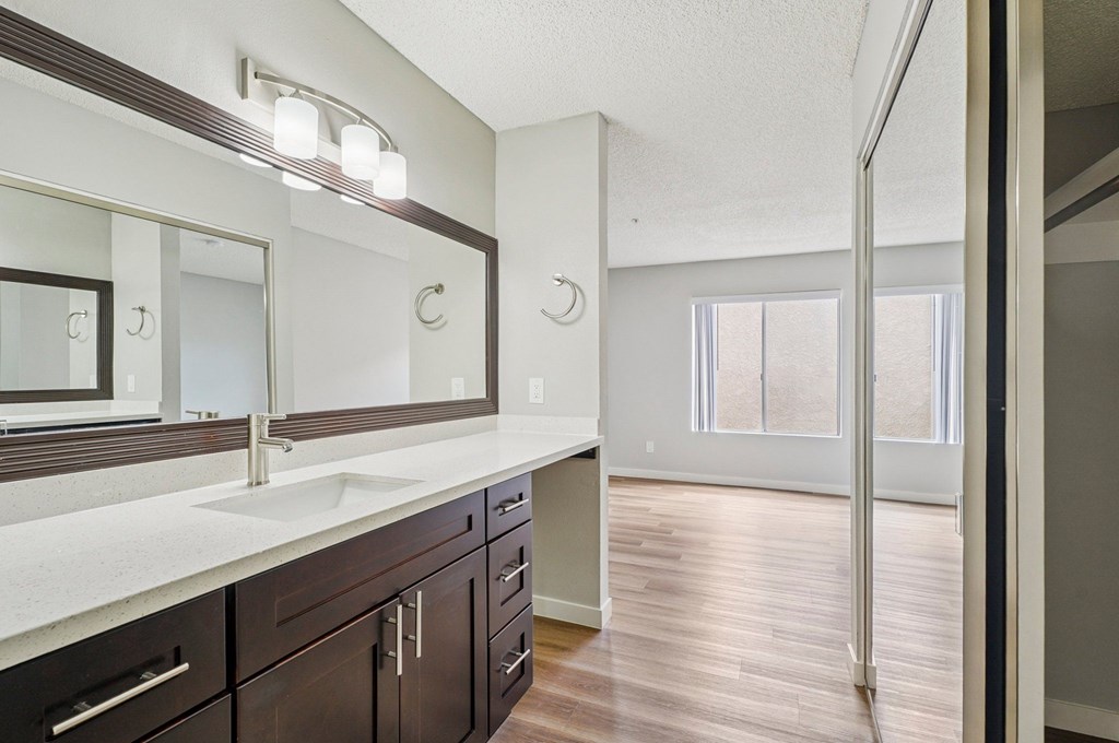 A bathroom with a sink, mirror, and wood floors.