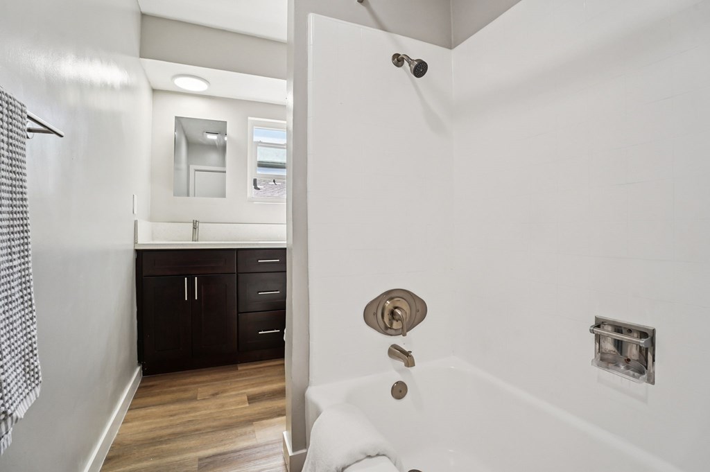 A white bathroom with a shower and a sink.
