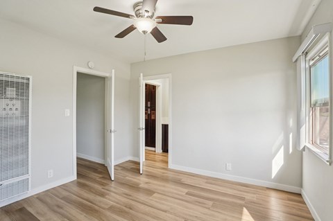 A room with a ceiling fan and wooden flooring.
