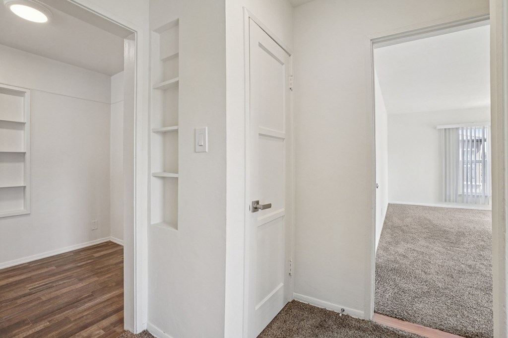 A white door is in the middle of a room with a grey carpet.