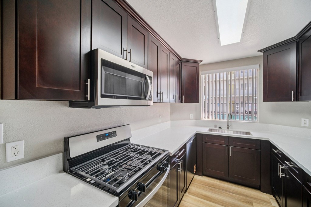 A kitchen with dark brown cabinets and a white counter top.