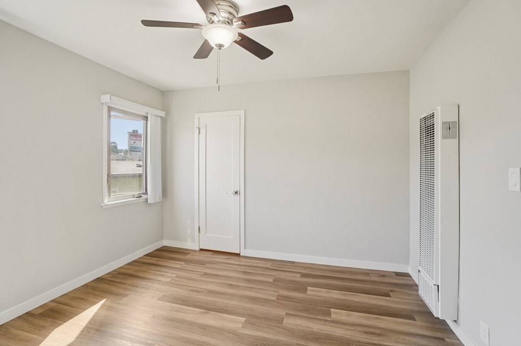 A room with a ceiling fan and wooden flooring.