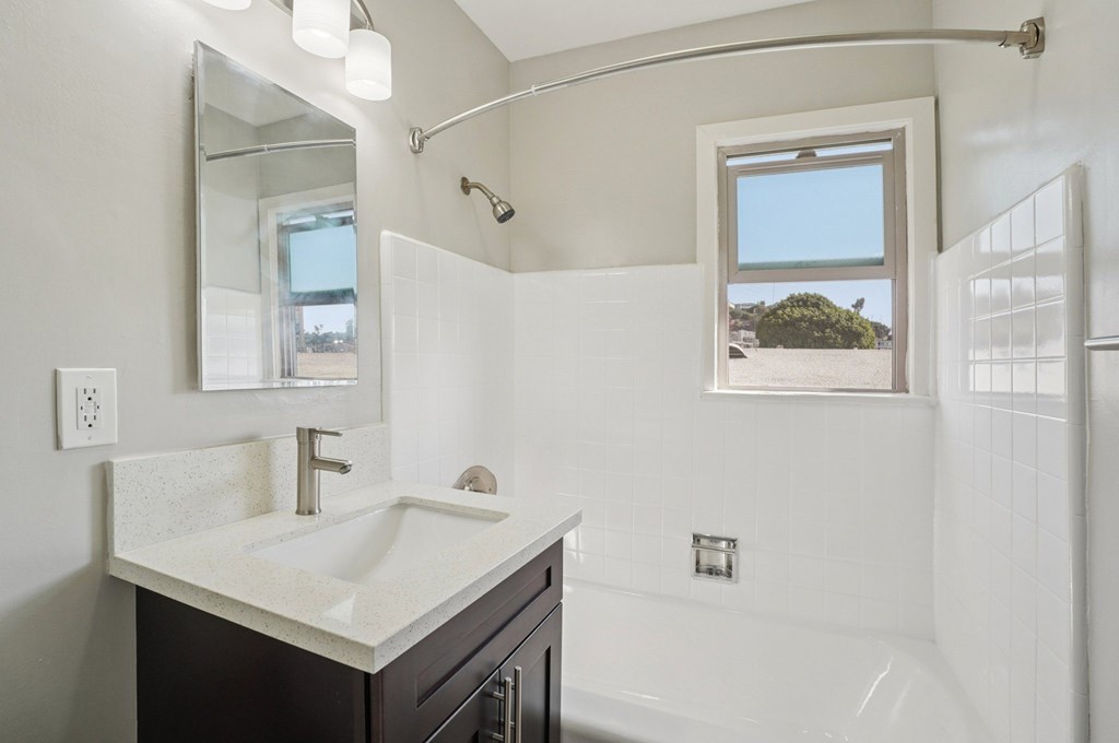 A bathroom with a white sink and a window.