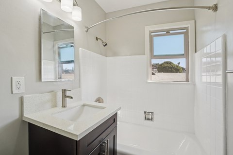 A bathroom with a white sink and a window.