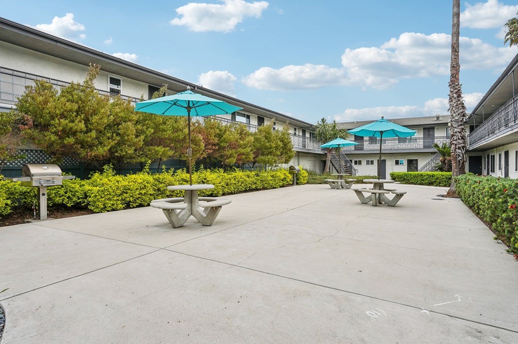 A sunny day at the courtyard with tables and umbrellas.