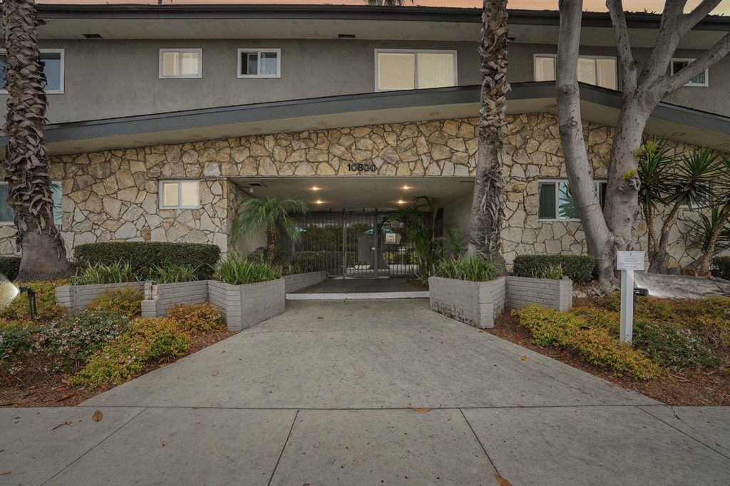 The front of a building with a stone facade and a walkway leading to the entrance.