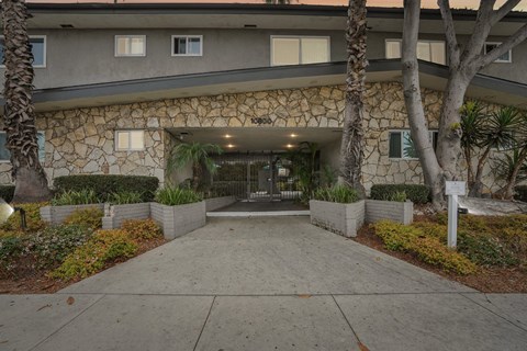 The front of a building with a stone facade and a walkway leading to the entrance.