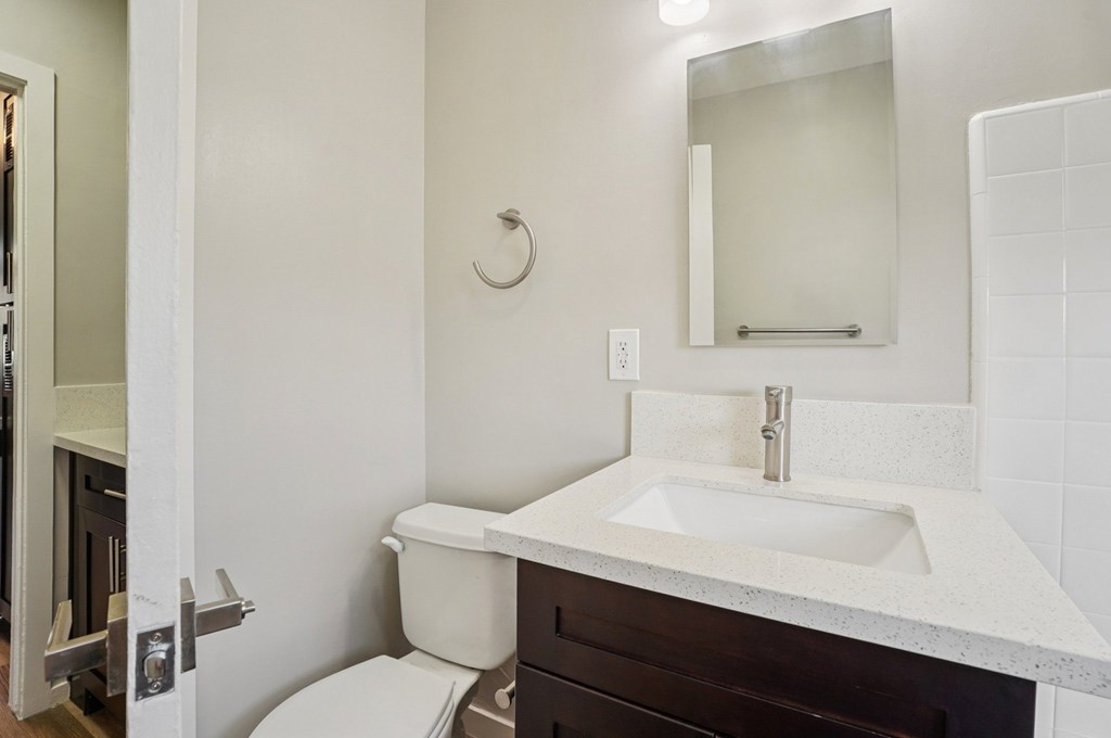 A white sink with a silver faucet and a white toilet in a bathroom.