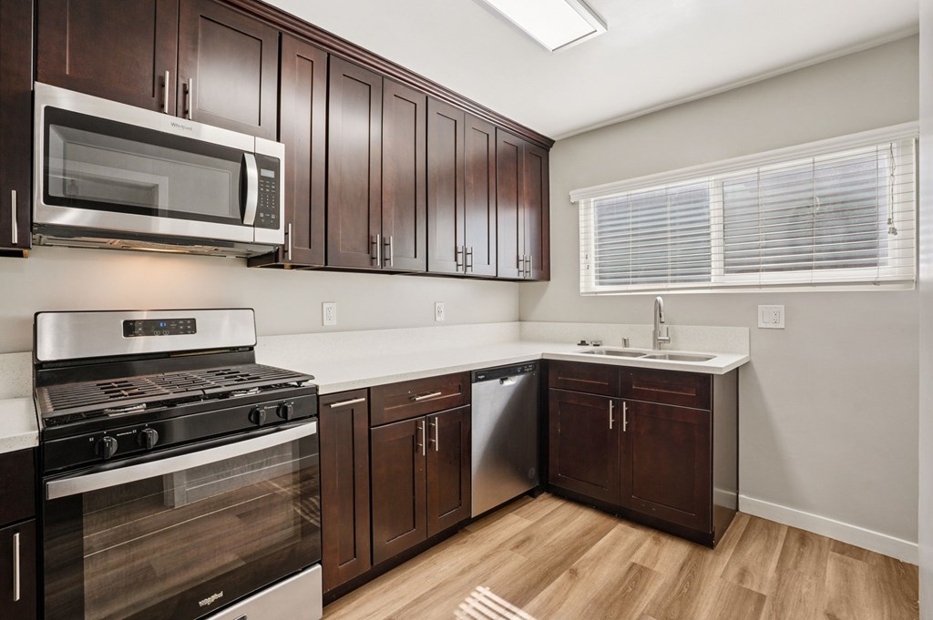 A kitchen with dark wood cabinets and stainless steel appliances.