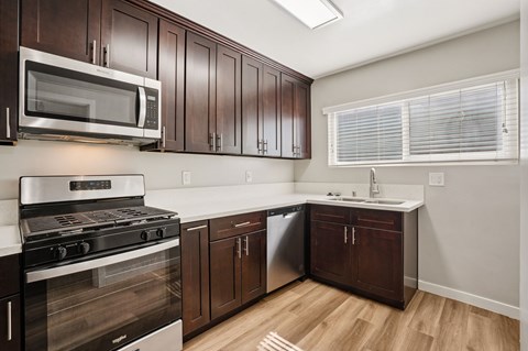 A kitchen with dark wood cabinets and stainless steel appliances.