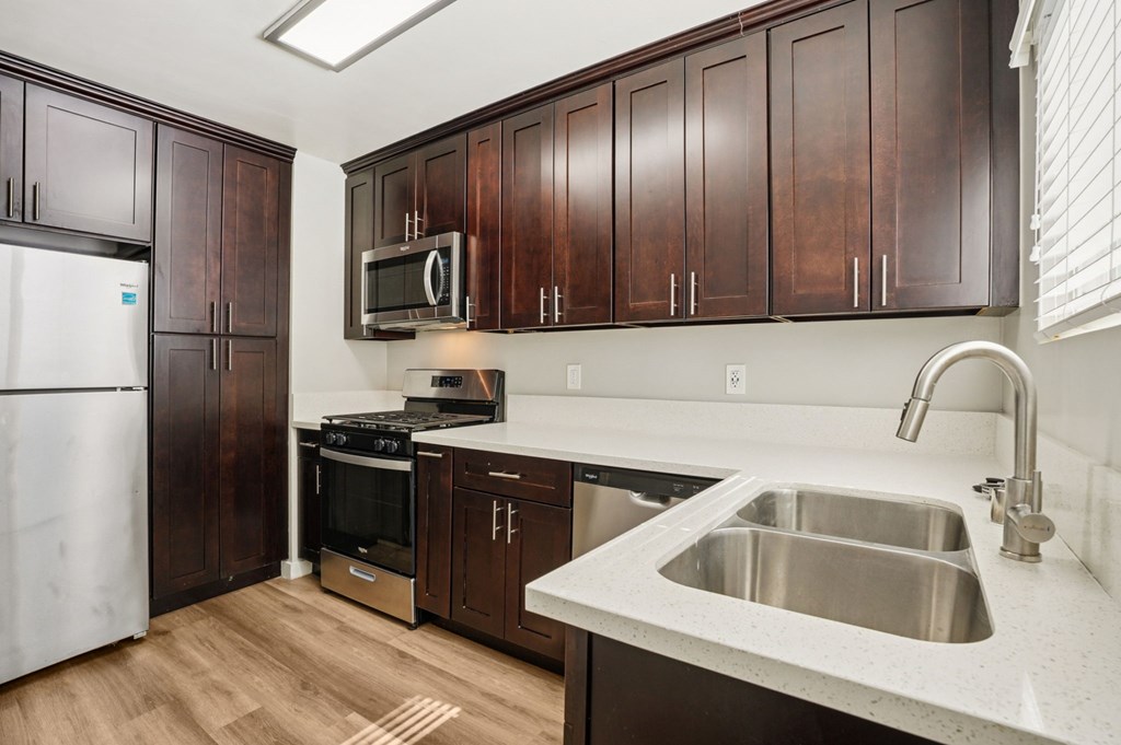 A kitchen with brown cabinets and a white sink.