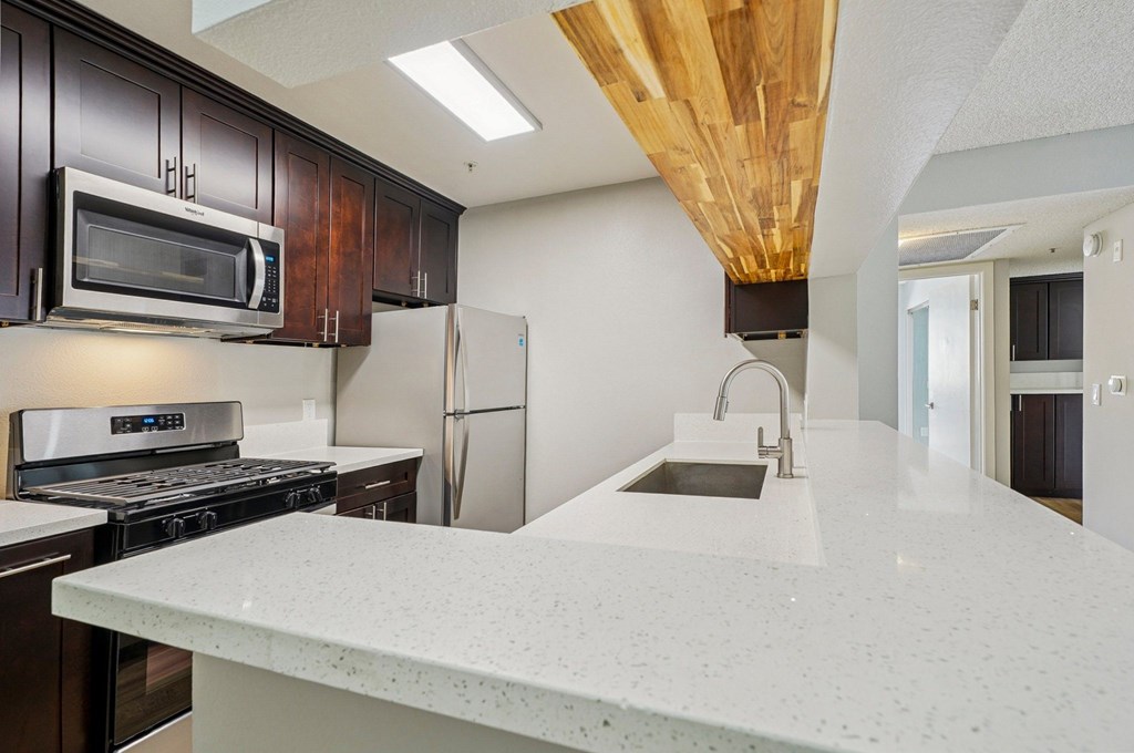 A kitchen with a white counter top and a stainless steel refrigerator.