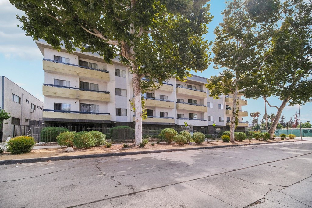 A street view of a residential area with apartment buildings and trees.