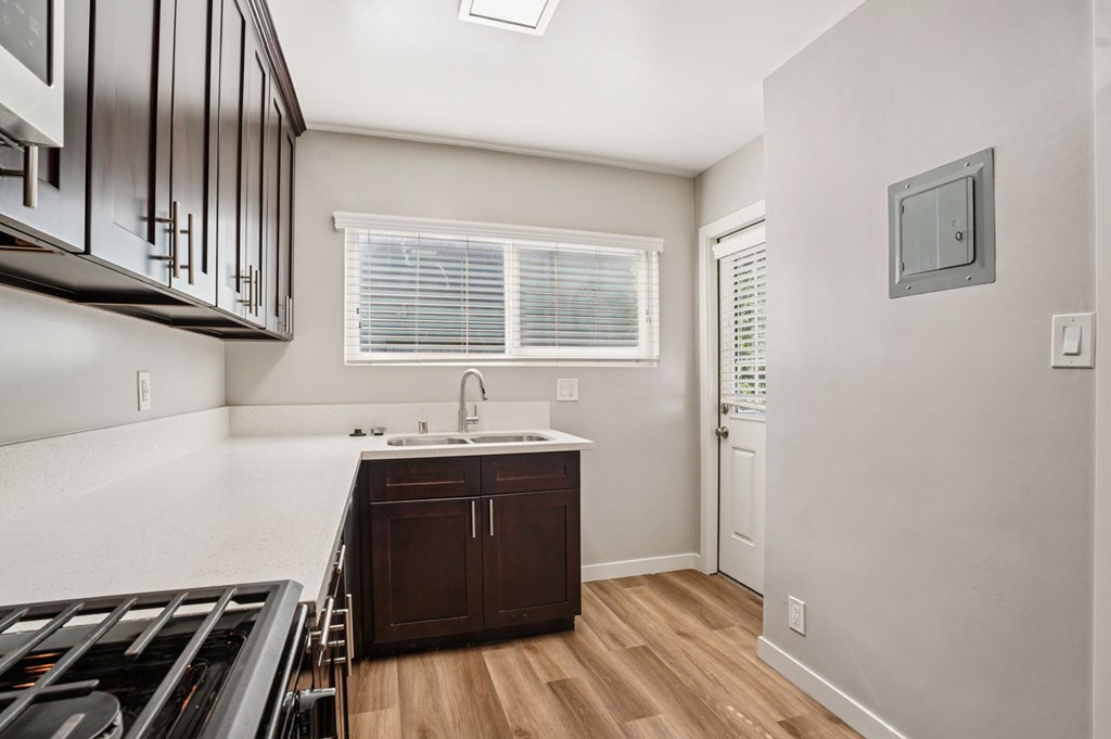 A kitchen with dark wood cabinets and a white countertop.