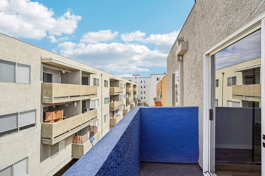 A blue wall separates two balconies of apartment buildings.