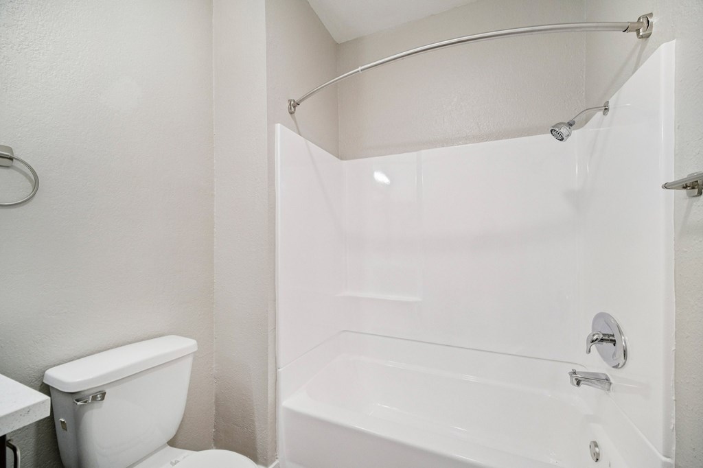 A white bathroom with a toilet, tub, and shower.